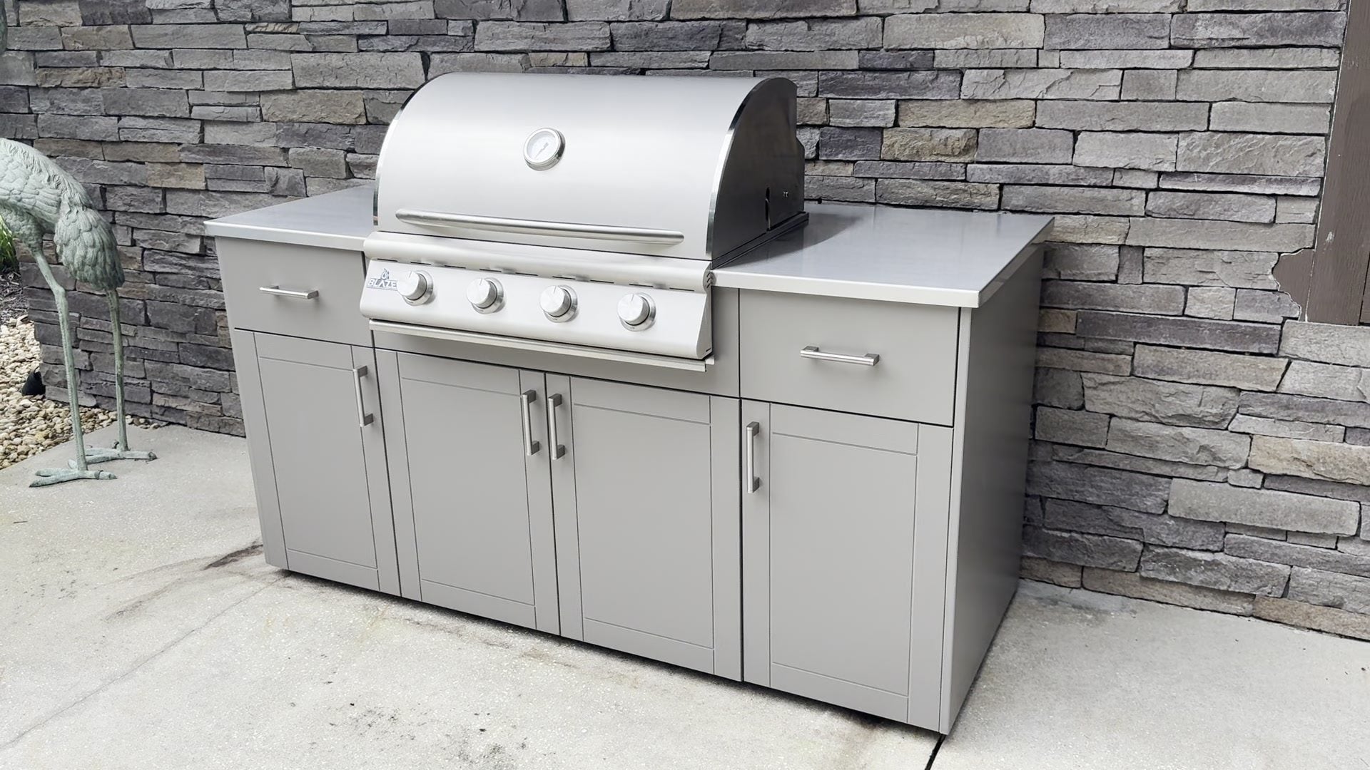 A welded aluminum outdoor kitchen with a Blaze grill installed against a stone wall on a Florida patio